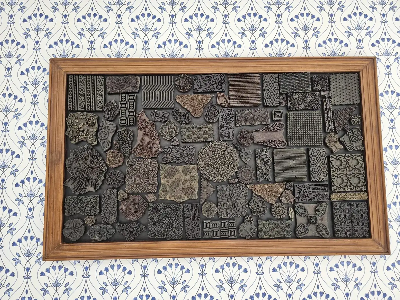 Carved relief printing blocks arranged in a wooden frame