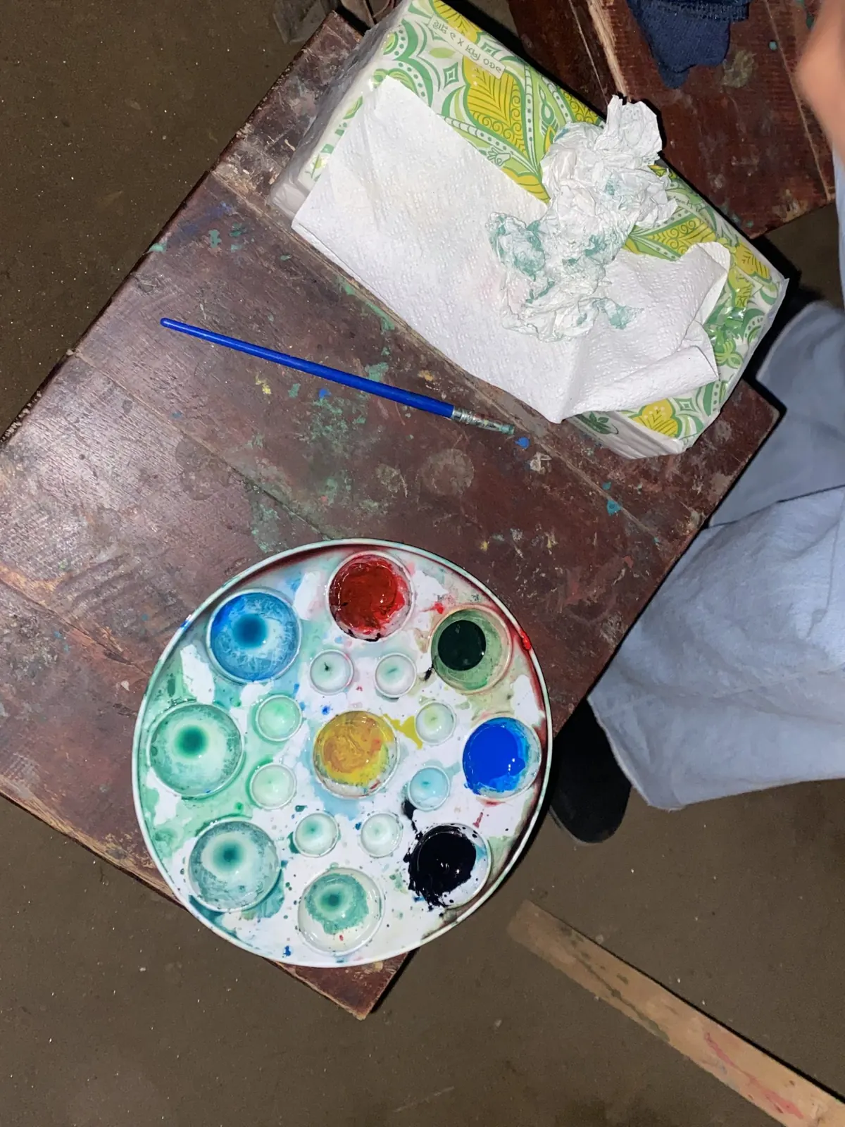 A watercolor palette and brush on a studio table